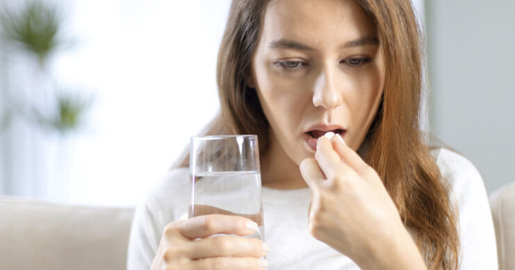 Young woman taking pill