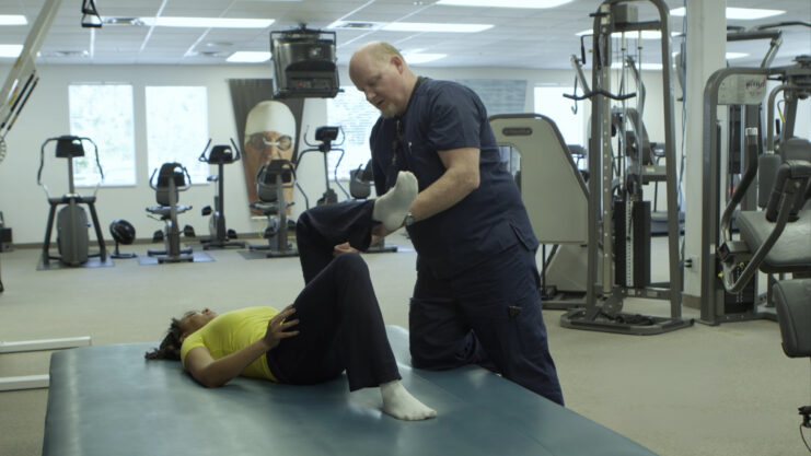 Physical therapist working with woman knee